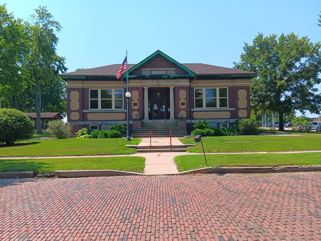 Side entrance of Richard A. Mautino Memorial library. A Carnegie building with an American flag by the side door.