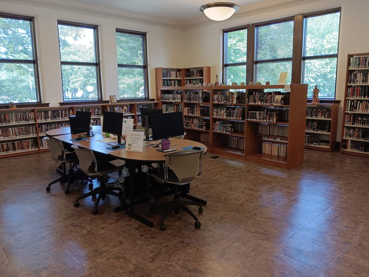 A table with 4 computer workstations. There are also several library shelves visible.