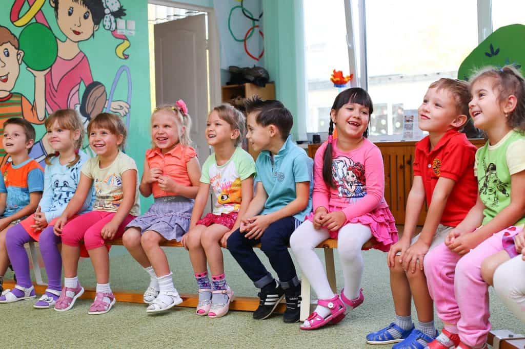 9 happy young children sitting on a bench